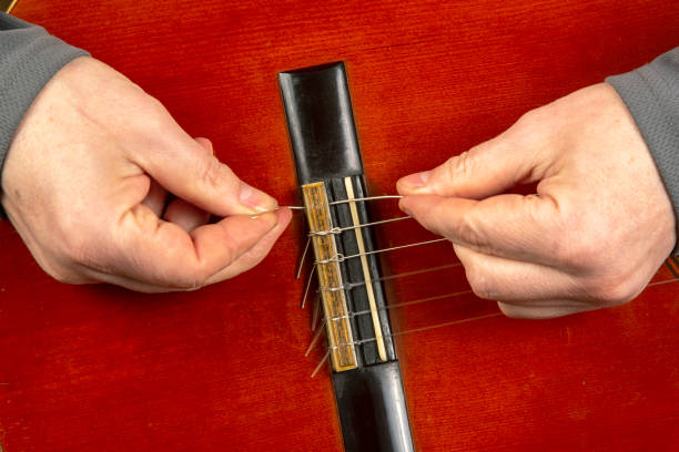 istock replacement and insertion of nylon strings in a classical guitar. lesson for a musician 1389483566
