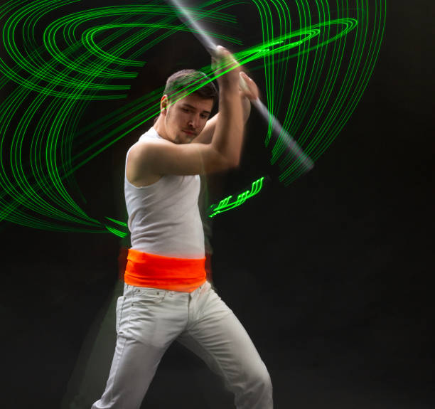 istock Light trail. Shooting with combined lighting. Young professional athlete plays with lighting equipment on a black background in mixed light. Working out in motion, action. Strength and energy. 1389483618