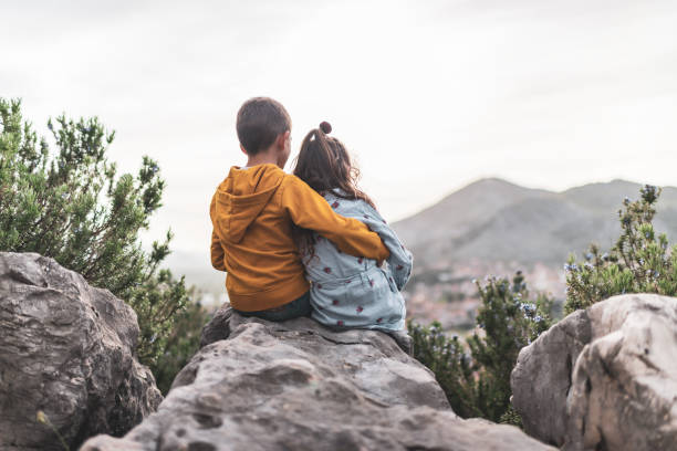 istock Young boy and girl enjoying mountains at sunset 1389484702