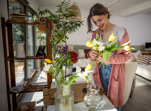 Young woman arranging her flowers at home on a beautiful sunny day