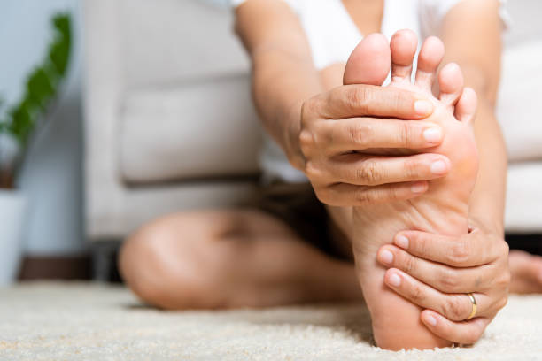 mujer asiática sintiendo dolor en el pie en casa - pie término anatómico fotografías e imágenes de stock