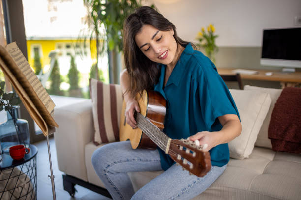 istock Young woman learning playing a guitar 1389486737