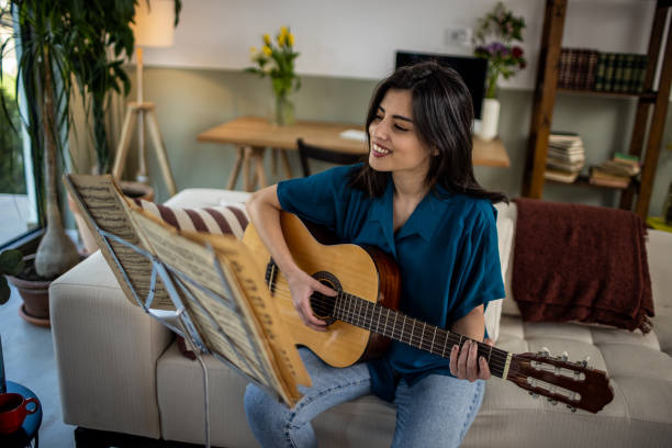 istock Young woman learning playing a guitar 1389486825