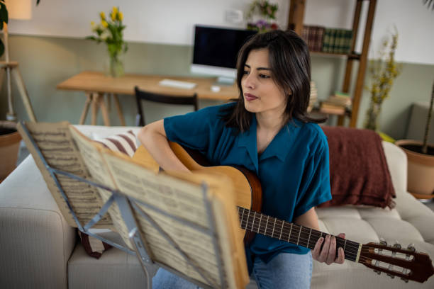 istock Happy woman is practicing acoustic guitar 1389488025