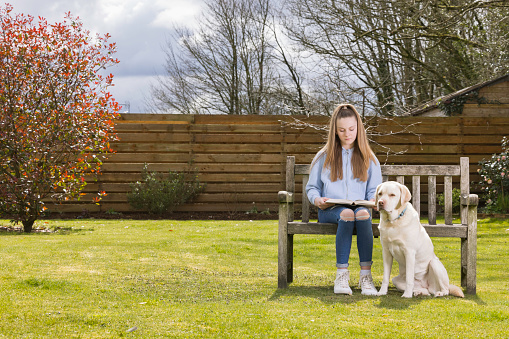 Pre-teen girl relaxing with her dog in the garden.