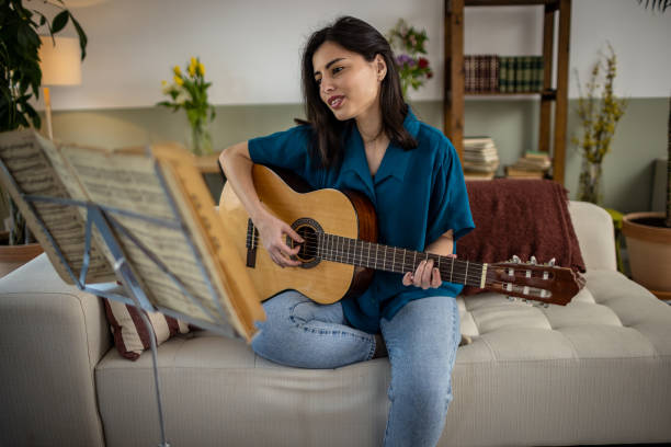 istock Happy woman is practicing acoustic guitar 1389488337