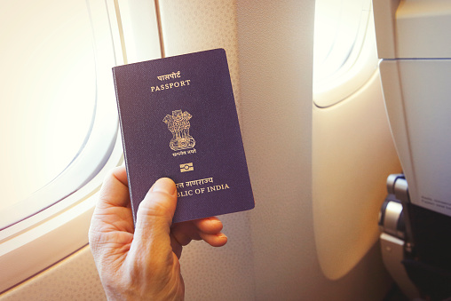 Detail of passenger's hand holding Indian passport on the airplane