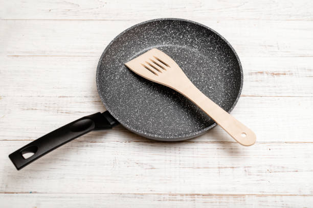 istock Frying pan with non-stick ceramic coating and spatula on a white wooden background. Cooking without sticking or oil. 1389491192