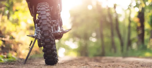 Part of a motocross wheel on a mound, with sunrise copyspace for your individual text. A part of a dirt road dirt bike in the forest