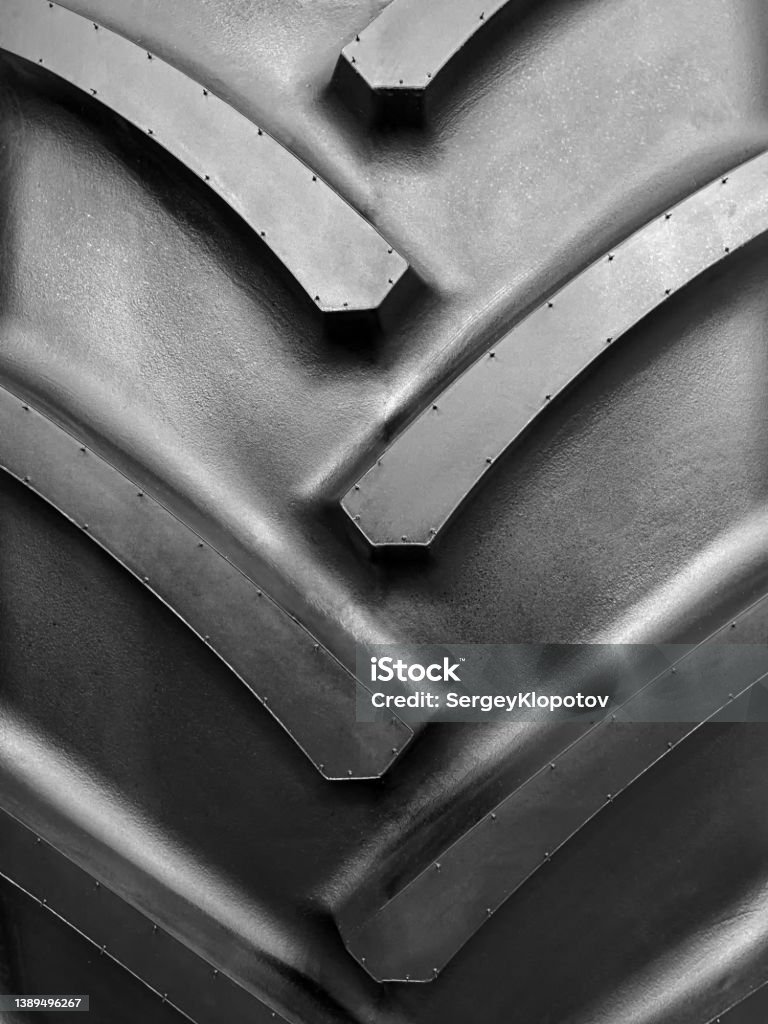 Closeup of the tread of a large rubber wheel Closeup of the tread of a large rubber wheel of a tractor or truck. Tire - Vehicle Part Stock Photo