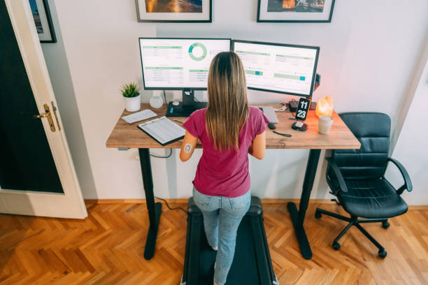 istock Woman working at standing desk is using credit card while walking at treadmill 1389496325