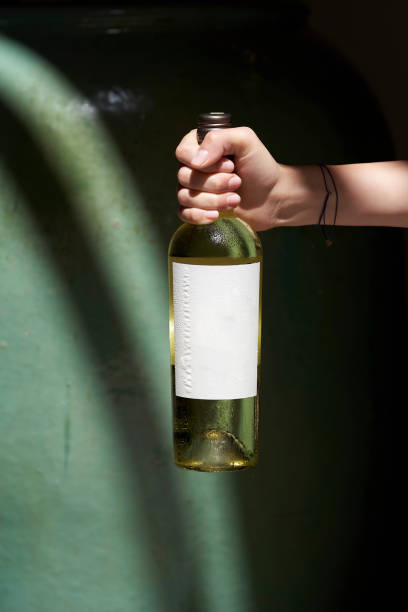 istock Hand holding bottle of wine, close-up. 1389497304