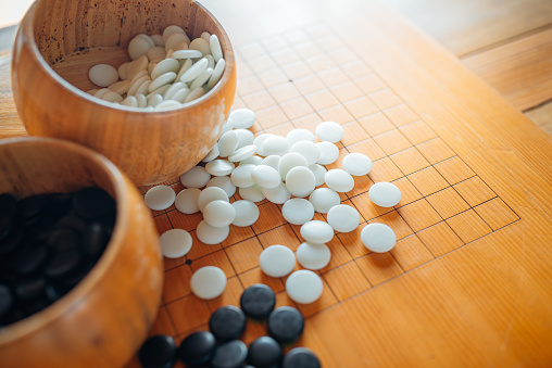Un conjunto de piedras de juego Go o Igo en los cuencos de madera en la mesa de cuadrícula. photo