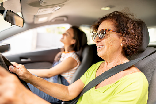 Mature woman smiling while giving her adult daughter a drive somewhere in her car