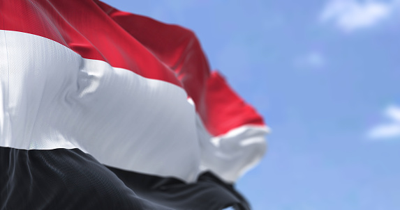 Detalle de la bandera nacional de Yemen ondeando en el viento en un día despejado photo