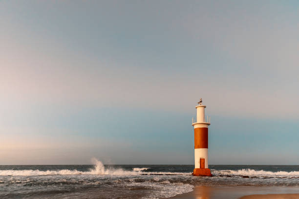 Waves crashing against Galinhos lighthouse at dusk