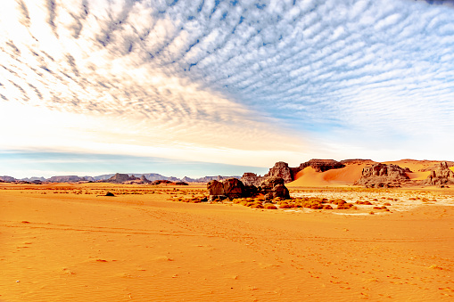 Colorful sand, Rocky Mountains, sky with sunlight diffusing in stratus clouds.