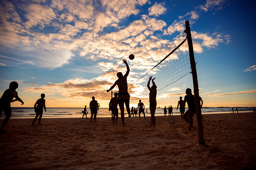 Silhouette of people playing beach volleyball at sunset