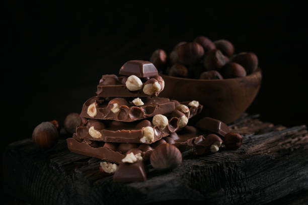 istock Pile of hazelnut milk chocolate and nuts on dark background 1389507279
