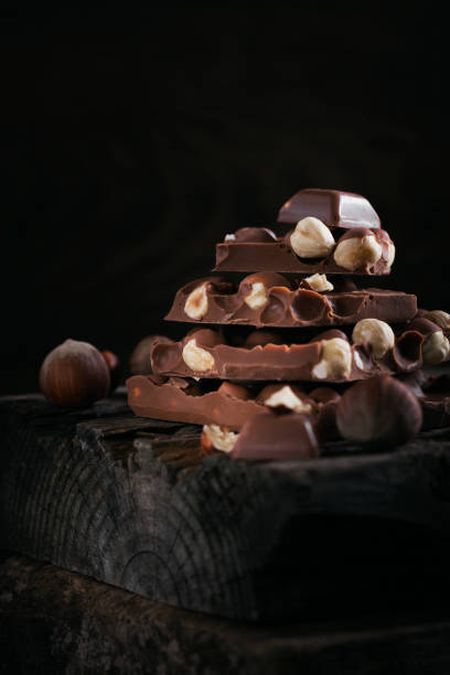 istock Pile of hazelnut milk chocolate and nuts on dark background 1389507281