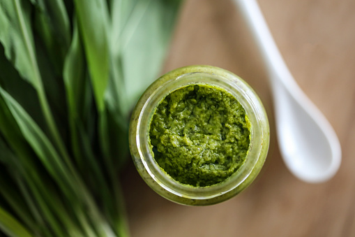 Homemade pesto made from fresh ramsons or wild garlic on wooden background.