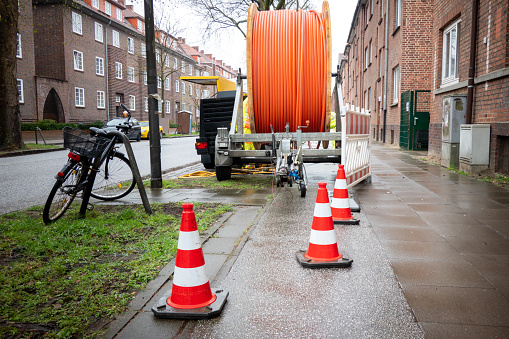 Internet cable laying on the outskirts. A large cable drum with fiberglass cable on the street in the outskirts of the city. Sluice covers are opened and the high-speed data cable is pulled into the shaft