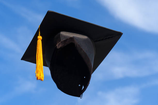 istock Graduation Caps Thrown in the Air blue sky on background 1389508615