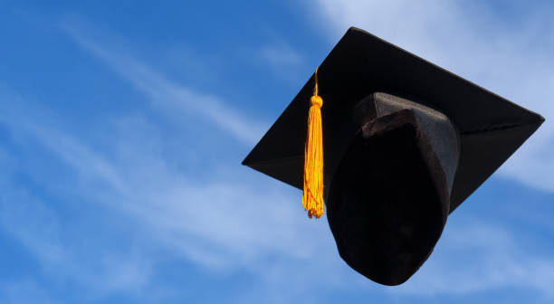 istock Graduation Caps Thrown in the Air blue sky on background 1389508621