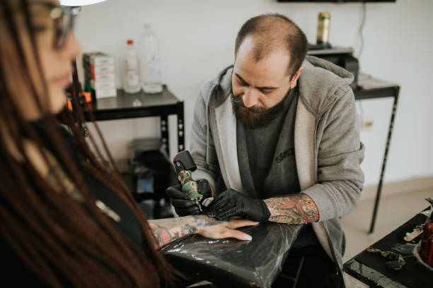 istock Young woman is getting tattoo on her hand 1389511486