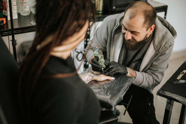istock Young woman is getting tattoo on her hand 1389511627