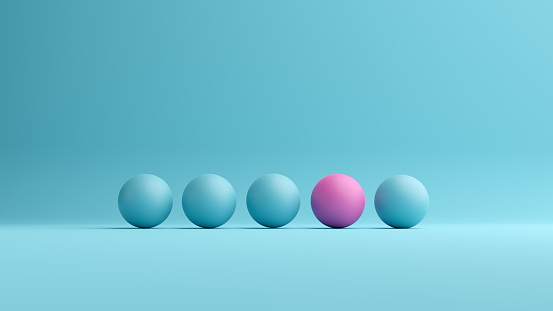 Pink ball stands out from the blue spheres. Difference, diversity, individuality, outstanding or unique concept.