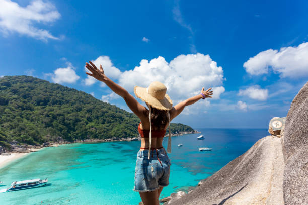 back view of women wearing a straw hat standing in view Beautiful sea and blue sky at Similan island, Phuket,Thailand. stock photo