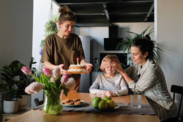 ребенок празднует свой день рождения с матерями-лесбиянками - cake birthday domestic kitchen child стоковые фото и изображения