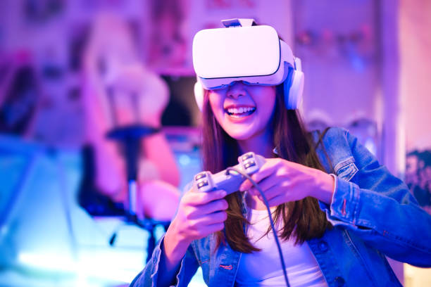 istock Young asian woman is using virtual reality headset. Neon light studio portrait. Concept of virtual reality, simulation, gaming and future technology.Asian woman play game in living room. 1389516316