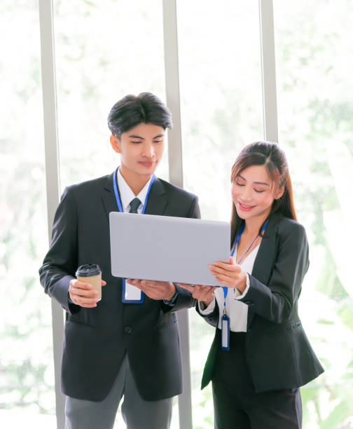 istock Two business person is standing while brainstorming together on a computer laptop with smile. 1389516535