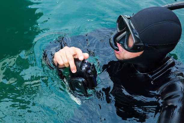 Confident diver checking sailboat with digital camera bottom after renting.