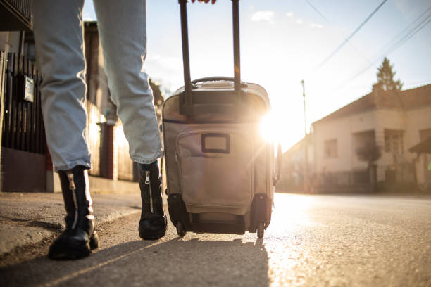 uma jovem puxa uma mala nas ruas da cidade enquanto caminha em direção à rodoviária - people traveling travel leaving disembarking - fotografias e filmes do acervo