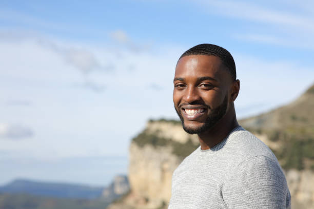 istock Happy man with black skin looking at camera in nature 1389525670