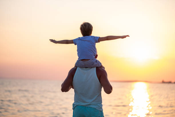 istock Dad and son on the beach playing and watching the sunset. 1389526970