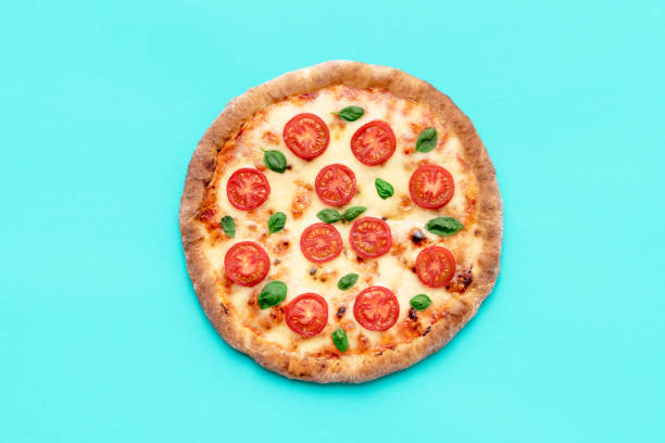 Vegetarian pizza above view, minimalist on a blue background Top view with a homemade pizza on a blue table. Ready to eat delicious vegetarian pizza made with tomato, mozzarella, and basil. pizza stock pictures, royalty-free photos & images