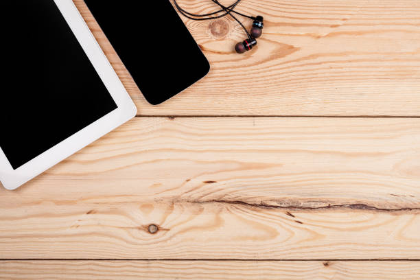 istock tablet computer, smartphone and headphones on a wooden table top view. background and workspace for writing text 1389527441