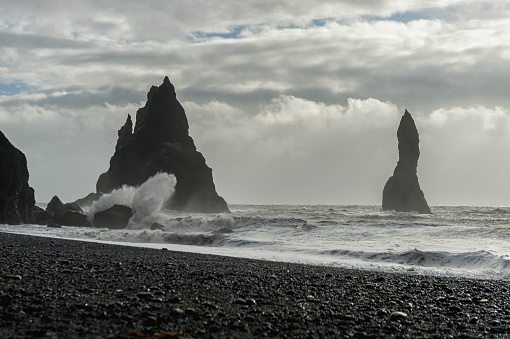 Black Sand Beach Reynisfjara in Iceland. Rocks in Water. Ocean Waves and Water Spach into Rocks.