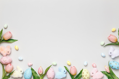 Easter composition. Tulips eggs toy rabbits on a gray background.