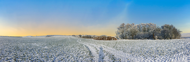 Mist on the ground over a snow-covered hillside landscape on the Mangfall valley in Upper Bavaria at dusk, Germany