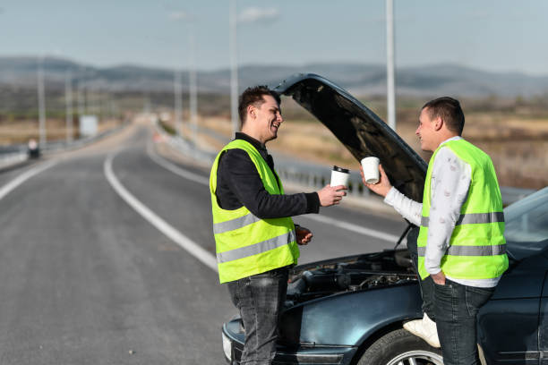 dois trabalhadores da assistência rodoviária do sexo masculino tomando café antes de transportar o carro - acidente evento relacionado com o transporte - fotografias e filmes do acervo