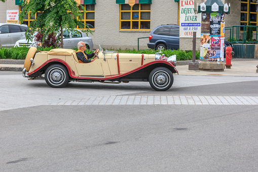 Senior man driving convertible vintage car on a street in Quebec City