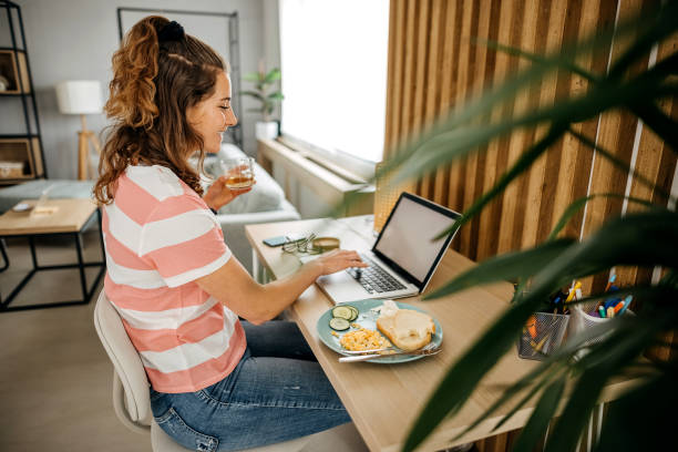 istock Women enjoying her dish while looking at laptop screen 1389543380