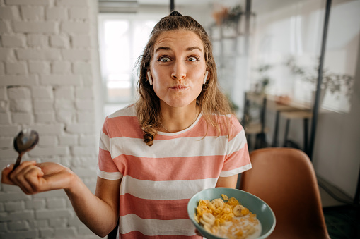 Woman is eating muesli for breakfast in her dining room