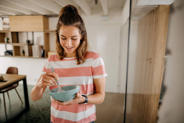 Woman smiling while tasting the food she cooked with a spoon