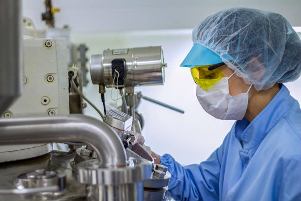 Pharmaceutical Machine Operator In Protective Clothing Pharmaceutical Technician Works In Sterile Environment At Pharmaceutical factory. Female Worker In Pharmaceutical Industry. pharmaceutical manufacturing machine stock pictures, royalty-free photos & images